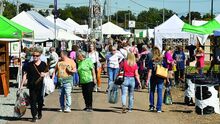 People stroll along through vendors on the Bloomsburg Fairgrounds during the Covered Bridge Arts and Crafts Festival Thursday.