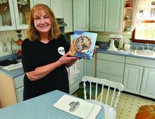 REBECCA GRASLEY holds a copy of her cookbook, “Pie Is Messy,” while in her mother’s Nescopeck kitchen Monday.