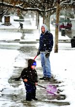 Harry Wolfe, 2, joins in shoveling snow with Todd Davis in Berwick Tuesday