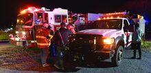 Volunteers gather around fire trucks, their lights on.