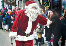 Santa Claus grabs onto the hand of a parade watcher along Front Street in Berwick Friday morning.