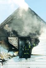 Berwick firefighter Jason Holloway rips the melted siding from the second story of this home at 1132 Fifth Ave. in Berwick late Friday morning.