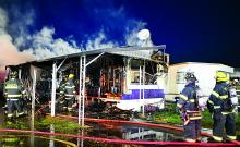 Firefighters work at the scene of a trailer fire in Berwick