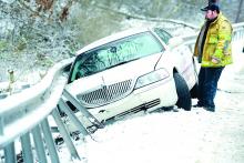 Jonathan Broadt closes the door of a wrecked Lincoln after talking to Rebecca Dice, whose husband, Art Dice, lost control of the car