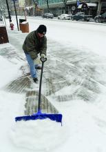 Courthouse maintenance worker Carl Mathews works to clear the sidewalk of snow