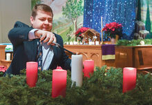 Pastor Adam Miller reaches in to light the center candle on the advent wreath during the first of three Christmas Eve services held at the Kulp United Methodist Church Friday afternoon. 