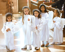 Paisley Taylor, far left, gets some guidance from Lillian Szmal as they make their way to their seats during the opening procession of the annual Christmas Pageant Sunday in the basilica of Saints Cyril and Methodius. Behind them, three other St. Cyril students, from left, Julianna Yost, Arwen Leal and Reese Burkett, prepare to take their seats as well.