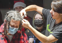 Danville student Ted Gordy, right, gets his turn at cutting one of the 16 hair braids off the head of teacher Mike Capita during Wednesday morning’s fundraiser. 