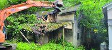 A man watches as equipment from Columbia Excavating knocks down a derelict house at 164 Main St. in Beach Haven.