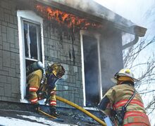 Firefighters run a hand line into a second floor window at the home on Walnut Street in Catawissa Tuesday afternoon as flames consume the attic of the home.