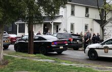 Police gather outside a house on Cemetery Street on Friday morning, where they arrested Steven Potter, one of two people charged with fleeing from police and dragging a police officer from the door of a moving vehicle.