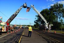 Washington Hose Company No. 2.(left) and Truck 19 Friendship Fire Company (right) hang a large American flag across Route 11 between two fire trucks in Memorial of 9/11.