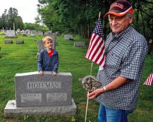 John Novak, at left, retired director of Veterans Affairs for Montour County, displays one of the 29 replaced brass veterans’ flag-holder markers. With him is his grandson, Thomas Egar, 5. Novak said about 2,500 flags are placed on veterans’ graves in the 51 cemeteries in Montour County