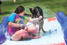 Rosalina Robustelli grabs the leash and takes German shepherd Axle Ellis for a wet ride down a cooling water slide in Mifflinville Wednesday afternoon. Heat and humidity are expected to moderate through this weekend, with temperatures in the mid 80s.