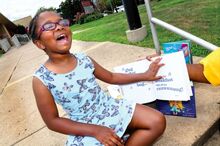 Harmonie Snowden, 7, talks about one of her favorite books while sitting on the steps of Memorial Elementary School in Bloomsburg Thursday afternoon. Snowden has been raising money by selling lemonade and doing extra chores at home to buy books for students at the school through Mrs. B’s Book Club.