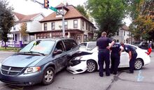 Ambulance personnel and police talk with the driver of the white Nissan Sentra following a collision with a Dodge Grand Caravan at the intersection of East and Fifth streets in Bloomsburg on Sunday afternoon.