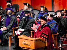 Bloomsburg University President Bashar Hanna, at the lectern, leads the applause for the College of Liberal Arts graduates during fall commencement on Saturday afternoon. 