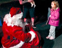 Aubrey Worrall, 5, Mifflinville, talks to Santa Claus as he makes his way out West Third Street in Mifflinville on Tuesday evening. Santa was accompanied by members of the Mifflin Township Forest Rangers and Fire Company No. 1. Firefighters will continue to tour with St. Nick tonight in the Hetlerville area.