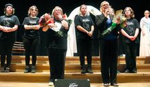 Melissa Richter, left front, cries as she gets a standing ovation led by choral and music director Carolyn Sweeney on Sunday. The salute followed the school’s musical production of “Little Women.” Richter is retiring after almost a decade at the helm of the school’s drama program.