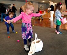 Madelynn Gray, 3, of Berwick stops gathering eggs Saturday morning to check out a prize Slinky-like spring toy she picked up during the third-annual members Easter egg hunt at the Berwick Golf Club. Usually held outside, the event was staged indoors due to the rain.