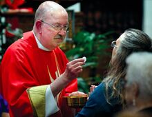 The Rev. Jerome A. Kleponis presents a host, Communion bread, while giving Communion during his first Mass at St. Columba Church in Bloomsburg on Sunday afternoon.