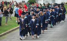 Mackenzie Baker, left, and Jessica Dodge lead the Millville High School senior class from the high school to the elementary Tuesday. The seniors make the annual walk in front of students and parents. The class graduates Friday.