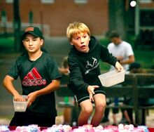 Sam Cumberland, left, and Arden Ditz, both 12 and both from Benton, toss ping pong balls at fish bowls while trying to win goldfish at the Benton Firemen’s Carnival in Benton Park on Thursday evening. The carnival continues tonight and Saturday night. The parade forms at 4 p.m. and moves at 5 p.m. on Saturday. The water battle will take place at the end of the parade by the Benton Dam.