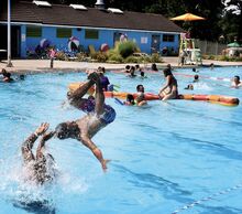 Jacob Caba does a backflip off the shoulders of Jose Luis Luna, both of Hazleton, in the water at Ber-Vaughn Pool in Berwick on Sunday afternoon. Temperatures reached the mid- to upper 90s for the sixth day in a row in the area.