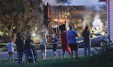 Neighbors, family and friends stand along police tape, above, while watching smoke rise from the fatal fire site at 733 First St. in Nescopeck early Friday.