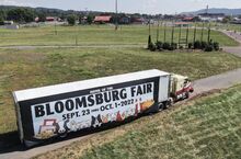 A Bloomsburg Fair sign hangs on the side of a tractor trailer in the fairgrounds parking lot Wednesday, near what remains of the old sign. It was destroyed in a windstorm earlier this year, and the town says that the fair needs to complete more paperwork before it signs off on a new billboard.