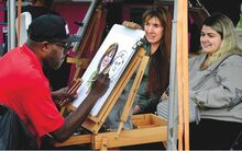 A sktech artist draws a caricature of two smiling women