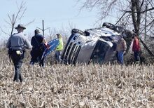 First responders carry equipment through a cornfield off Horse Farm Road to reach a pickup that went off Interstate 80 and wrecked in the field.